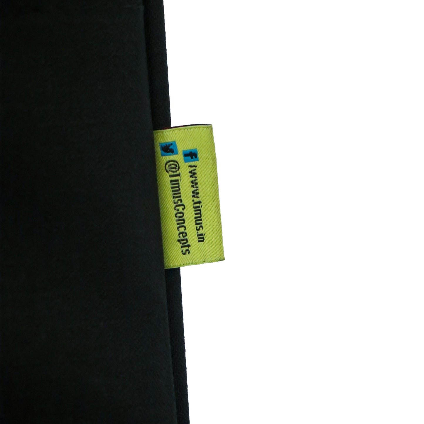 Close-up of the Timus brand tag on Salsa Plus black luggage, displaying the stitched logo along with social media handles for Facebook and Twitter.