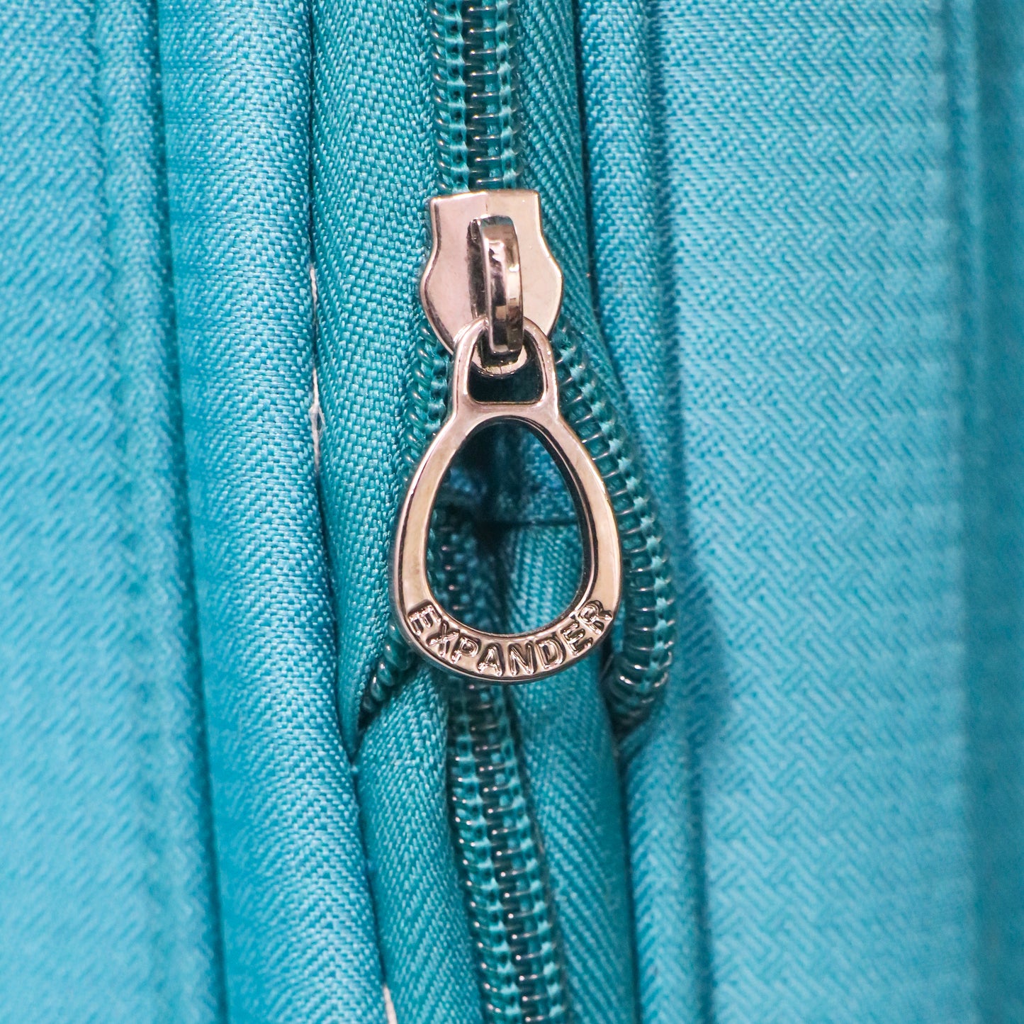 Close-up view of the expandable zipper on blue Salsa Plus luggage, allowing extra packing space when needed.