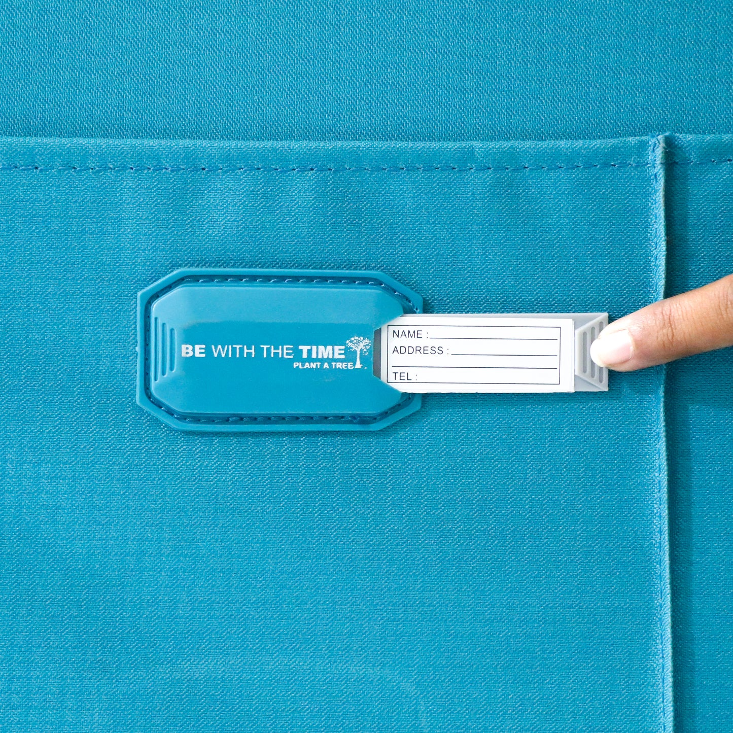 Close-up of the name tag slot on blue Salsa Plus luggage with the name card slightly visible for easy identification.