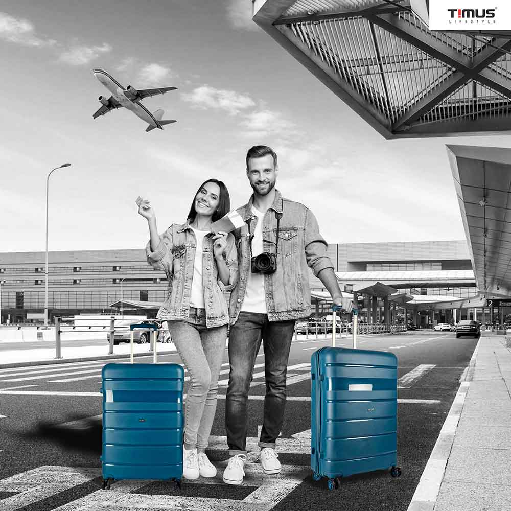 A man and woman standing at the airport holding blue sunlite hard trolley bags, showcasing a travel-ready lifestyle with stylish luggage