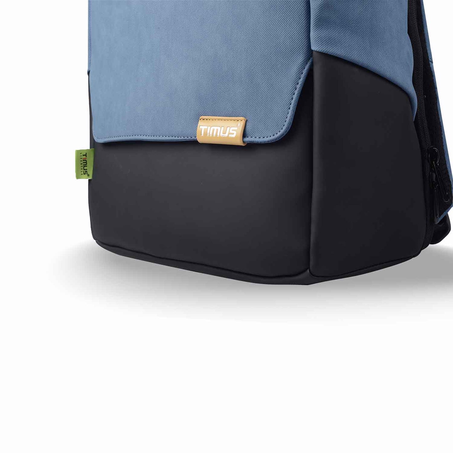 Close-up of the bottom front of the Timus Magnet Overnighter backpack in blue, highlighting the Timus logo tag and green side label on the smooth black base.