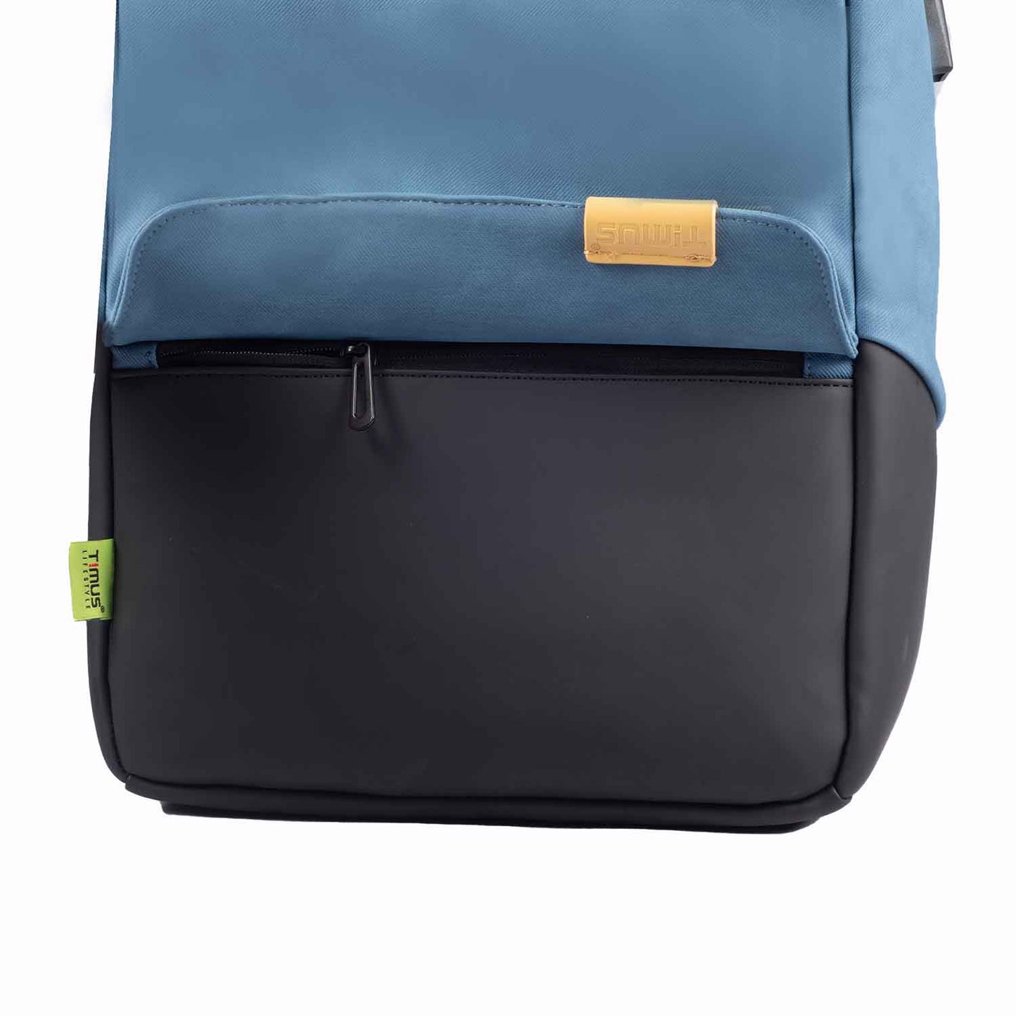 Close-up front view of the Timus Magnet Overnighter backpack in blue showing the open front zipper pocket, tan Timus logo tag, and green side label.