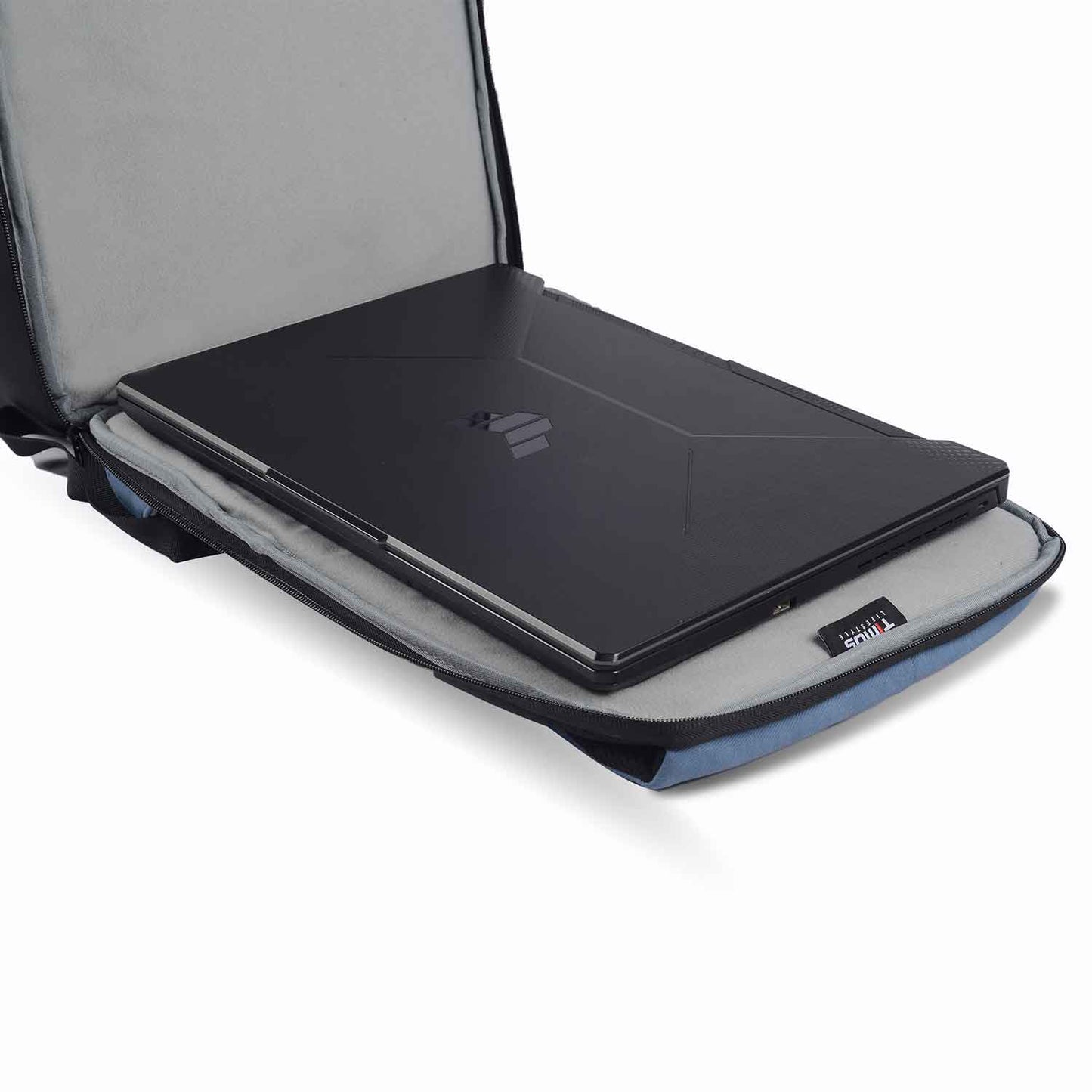 Laptop compartment of the Timus Magnet Overnighter backpack in blue with a black laptop placed inside the padded sleeve and Timus branding visible.