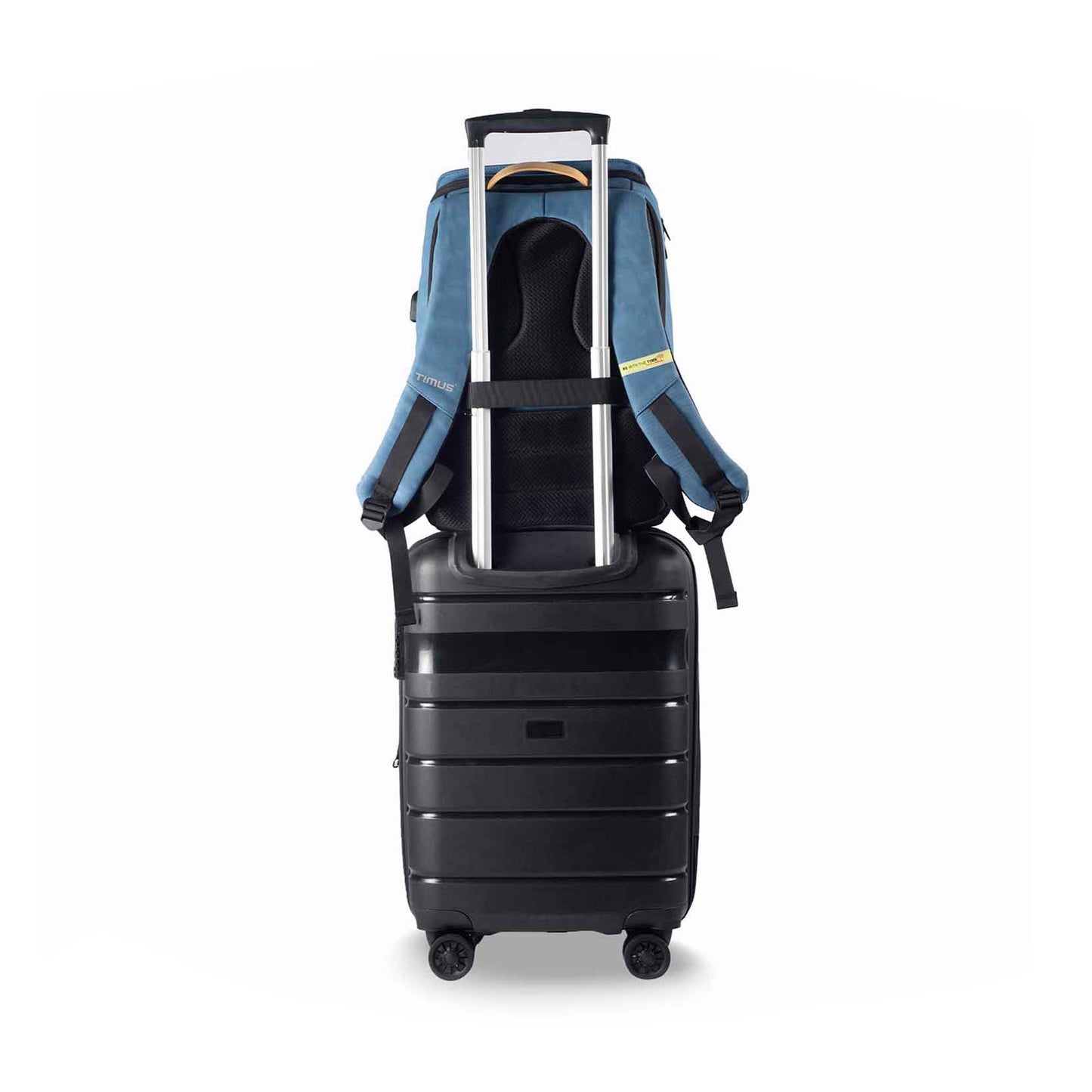 Back view of the Timus Magnet Overnighter backpack in blue attached to the handle of a black suitcase, showcasing luggage padded straps and carry handle.