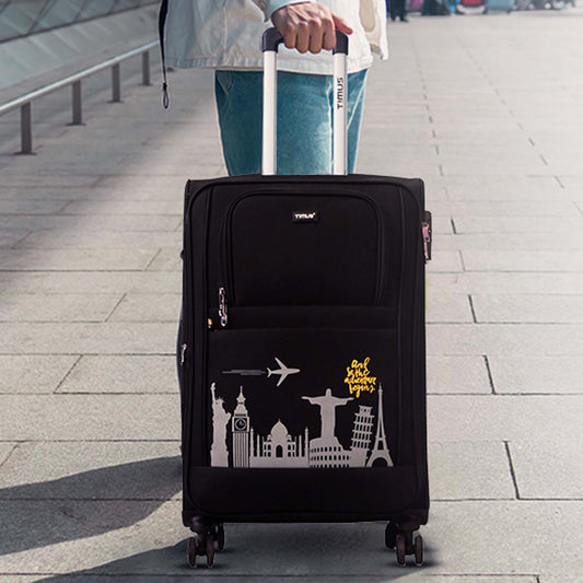 Black suitcase with travel-themed design being pulled by a person on a pavement.
