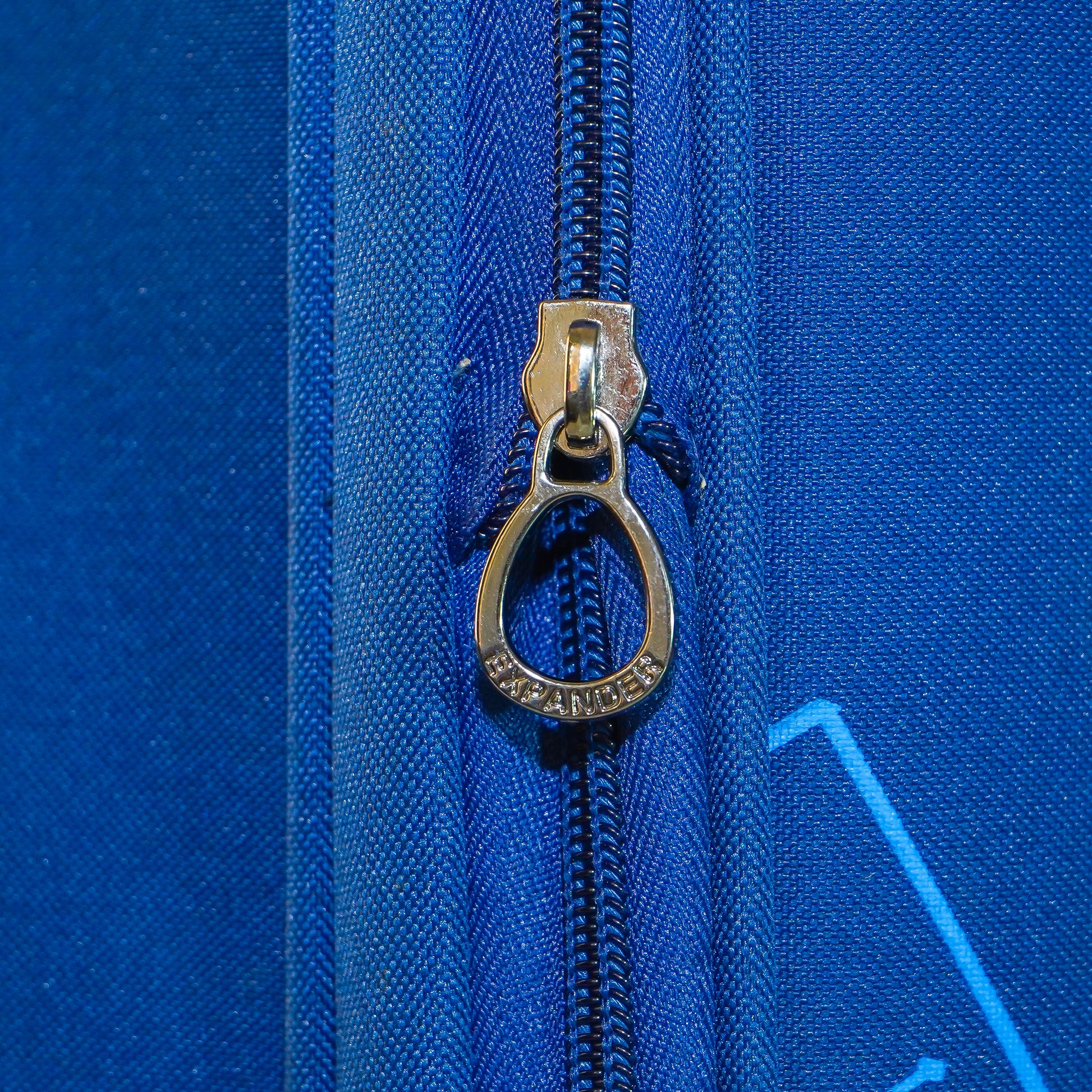Expandable zipper chain on blue Flash Plus luggage to increase capacity