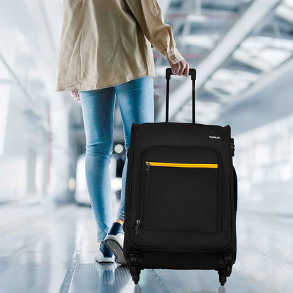 Traveler pulling black Nexon soft luggage detail in airport walkway, showcasing mobility and travel-ready design.