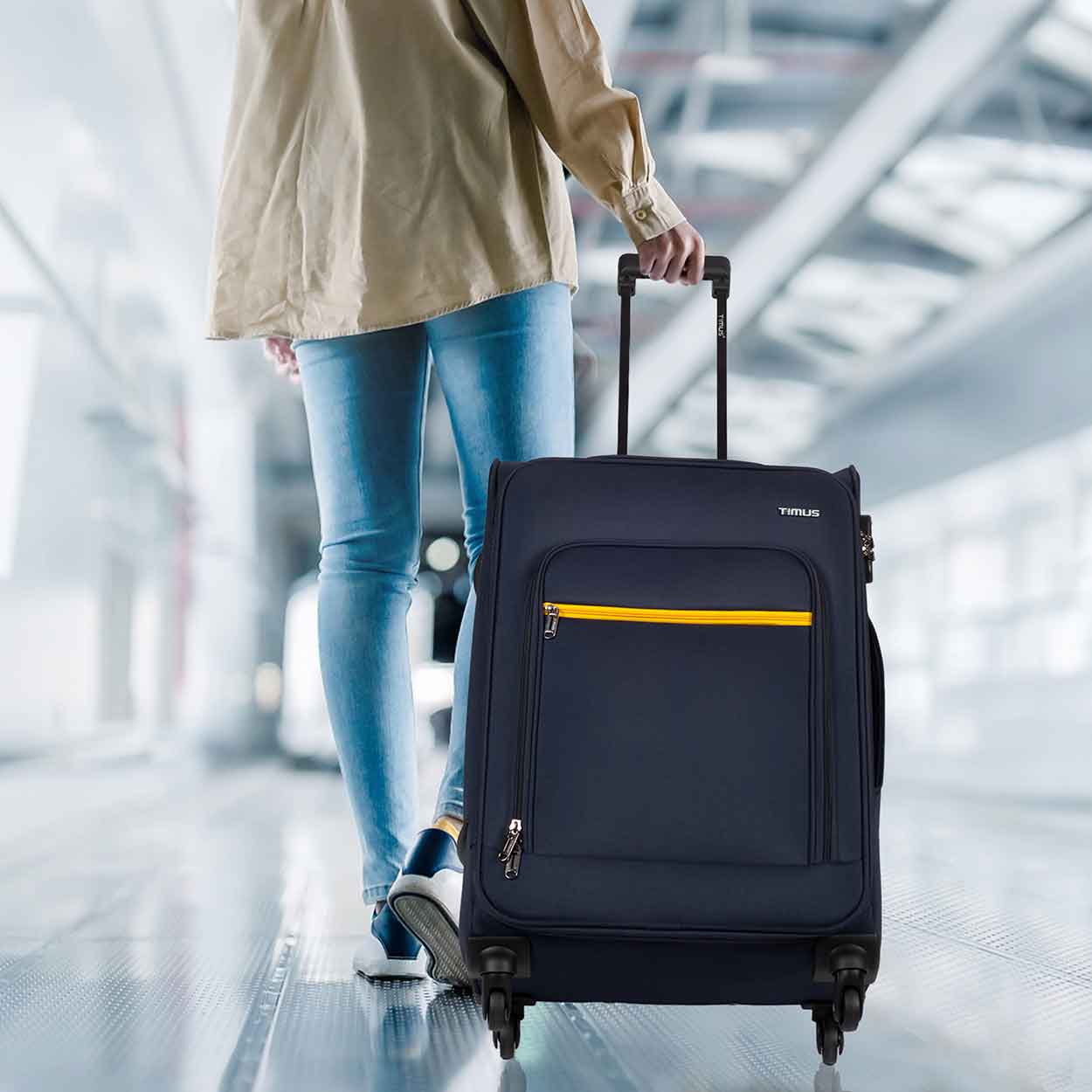 Traveler pulling blue Nexon soft luggage in airport walkway, showcasing mobility and travel-ready design.