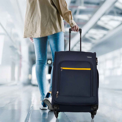 Traveler pulling blue Nexon soft luggage in airport walkway, showcasing mobility and travel-ready design.