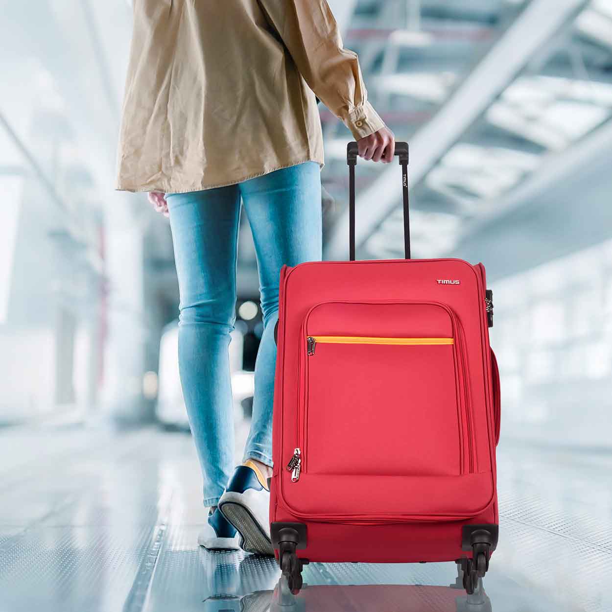 Traveler pulling red Nexon soft luggage in airport walkway, showcasing mobility and travel-ready design.