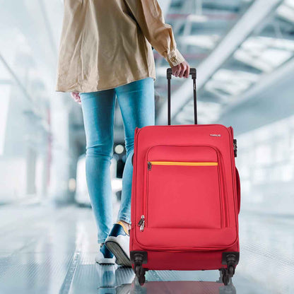 Traveler pulling red Nexon soft luggage in airport walkway, showcasing mobility and travel-ready design.