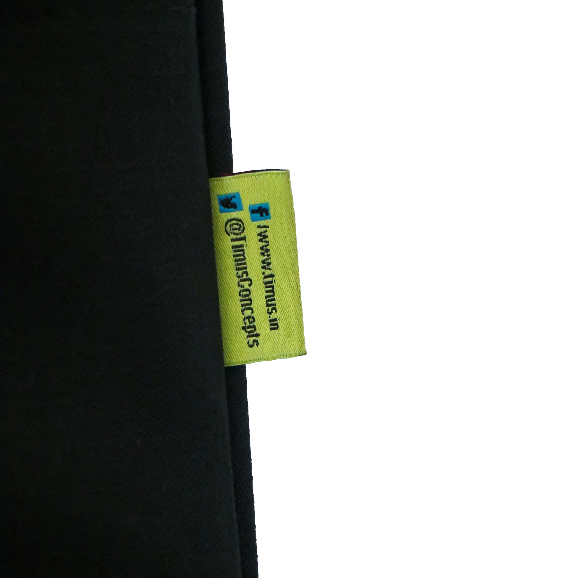 Close-up of the Timus brand tag on Salsa Plus black luggage, displaying the stitched logo along with social media handles for Facebook and Twitter.

