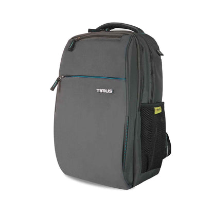 Left front angled view of the Timus Cyprus backpack in grey, showing a front zipper pocket with the Timus logo, a top handle, and a mesh side pocket with a Timus brand tag.