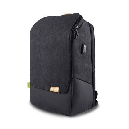 Left front angled view of black Timus Magnet Overnighter professional backpack showing textured fabric flap with leather-like bottom, small Timus logo patch, USB charging port on the side, and green Timus tag on a white background.