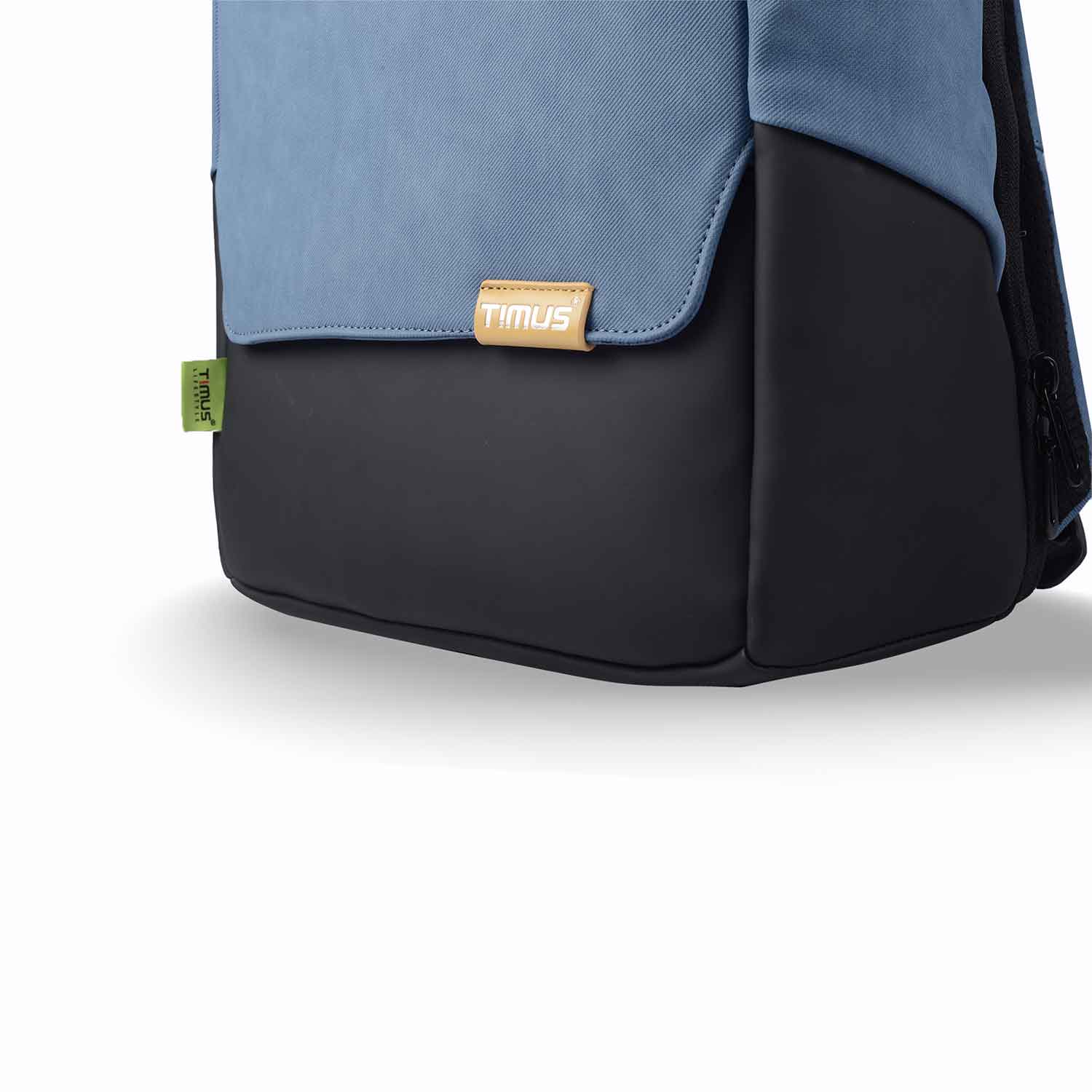 Close-up of the bottom front of the Timus Magnet Overnighter backpack in blue, highlighting the Timus logo tag and green side label on the smooth black base.