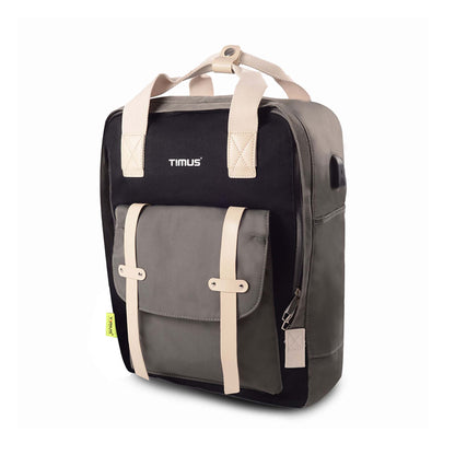 Left front angled view of the Timus Miami black urban backpack featuring a grey front pocket with beige straps, closed zipper for main compartment, visible USB charging port and timus brand logo at front.