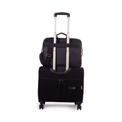 Black Timus New York laptop carry-on bag shown from the back, securely attached to the handle of a black rolling suitcase with dual spinner wheels on a white background.