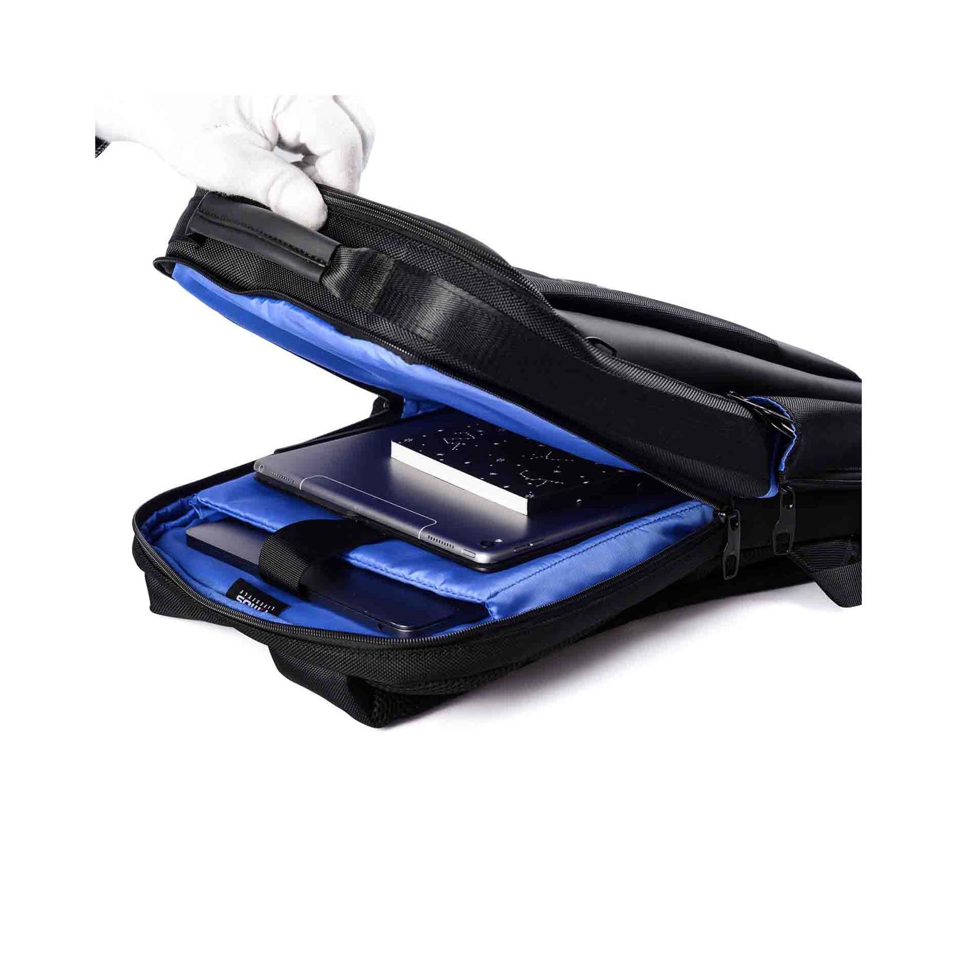 Open view of the Paris laptop backpack showing a blue interior with a padded laptop compartment holding a laptop and a book, with a hand wearing a white glove lifting the top flap.